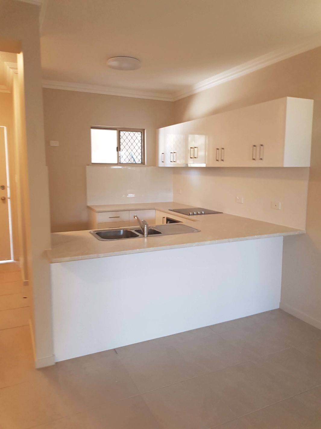 An Empty Kitchen With White Cabinets and a Sink — Omni Builders In Bungalow, QLD