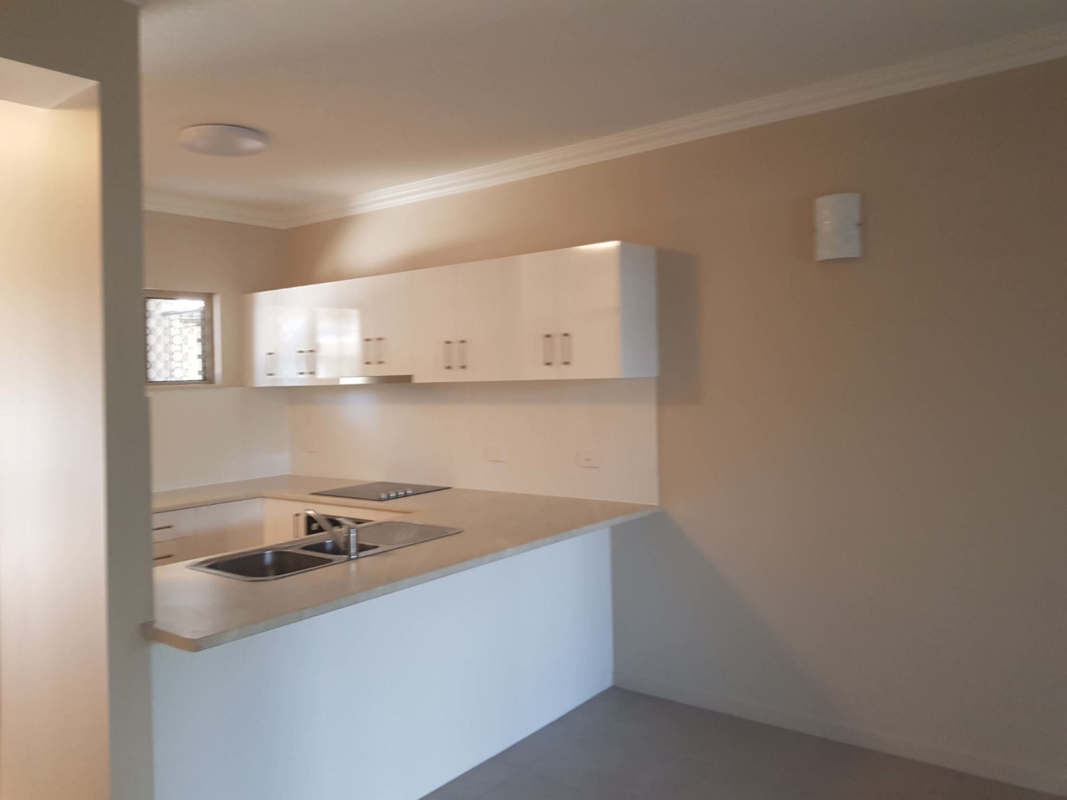 A Kitchen With White Cabinets , a Sink , and a Window — Omni Builders In Bungalow, QLD