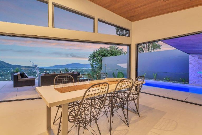 A Dining Room With a Table and Chairs and a View of a Swimming Pool — Omni Builders In Bungalow, QLD