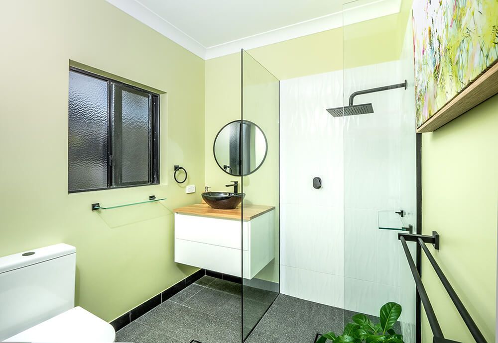 A Bathroom With a Toilet , Sink , Shower and Window — Omni Builders In Bungalow, QLD