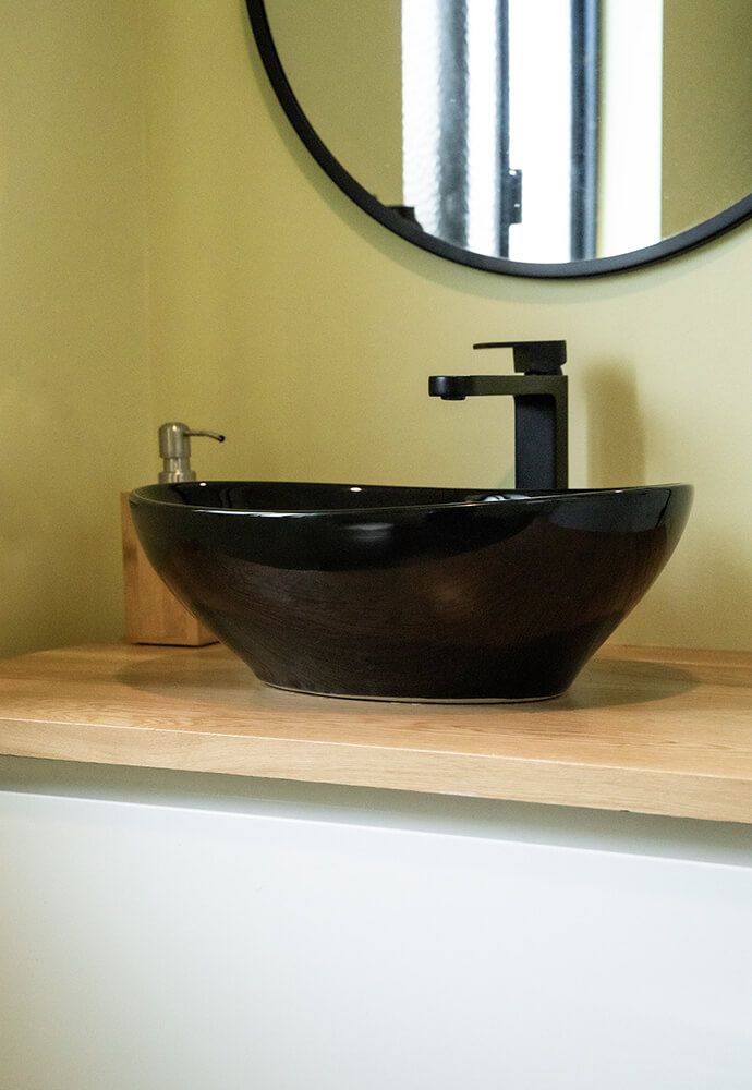 A Black Sink is Sitting on a Wooden Counter in a Bathroom — Omni Builders In Bungalow, QLD