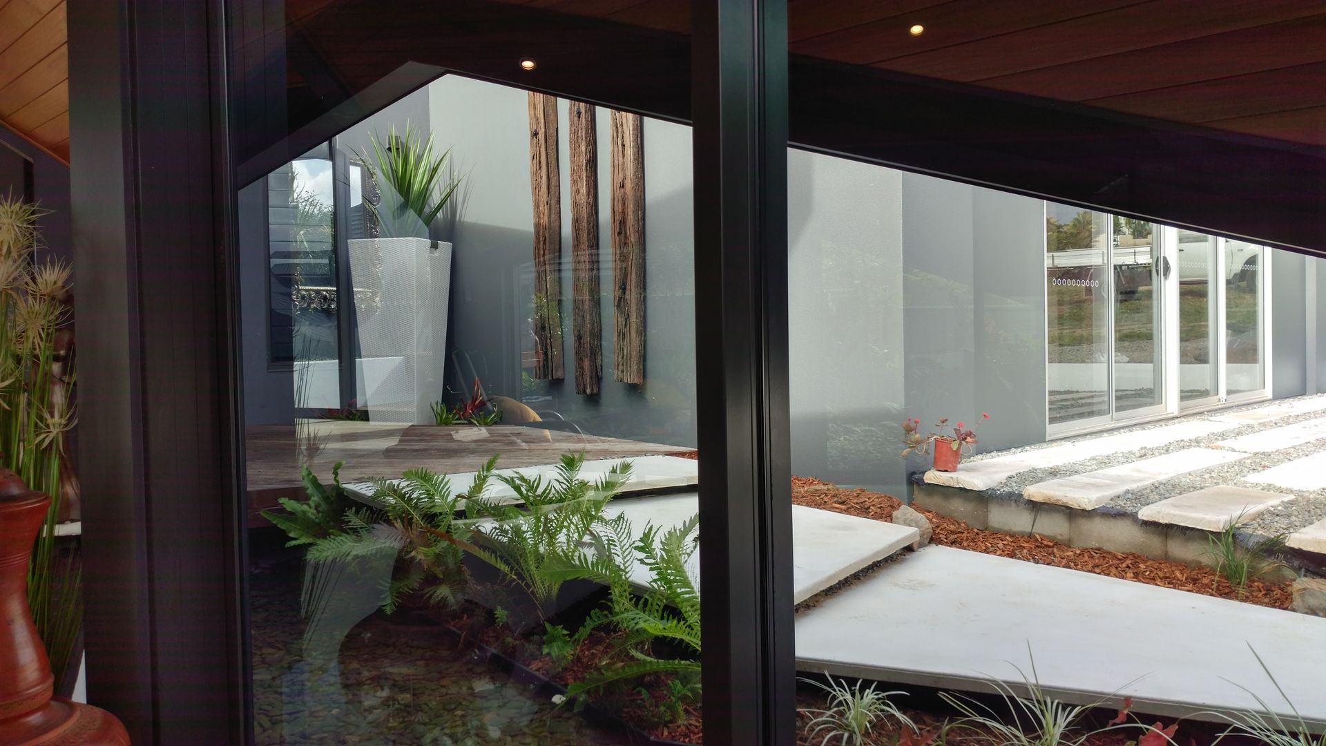 A View Of A Garden Through A Window Of A House — Omni Builders In Mareeba, QLD