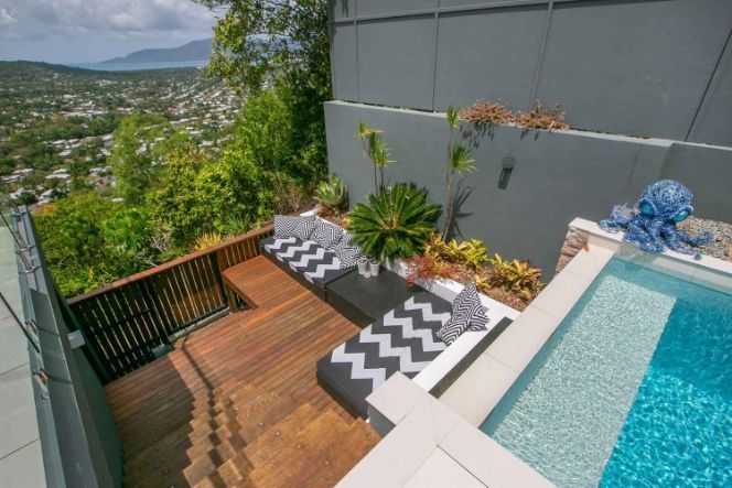 An Aerial View of a Swimming Pool With a Wooden Deck and Stairs Leading to It — Omni Builders In Bungalow, QLD