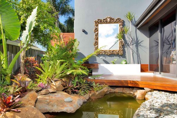 A Pond in the Backyard of a House With a Mirror on the Wall — Omni Builders In Bungalow, QLD