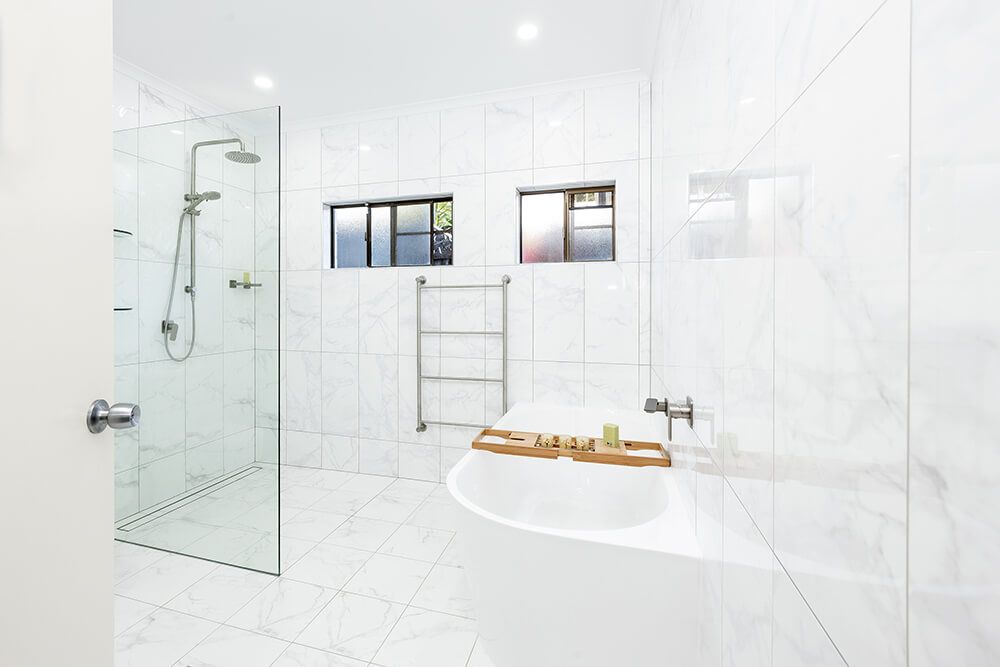 A Bathroom With a Bathtub , Shower , and Window — Omni Builders In Bungalow, QLD