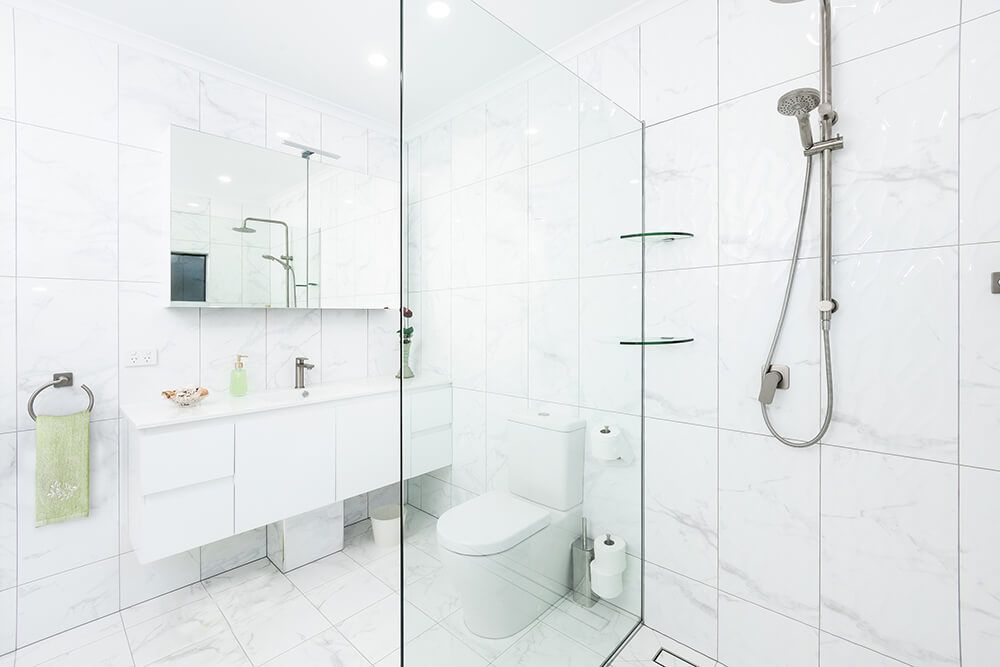 A Bathroom With a Sink , Mirror , and Blue Cabinets — Omni Builders In Bungalow, QLD