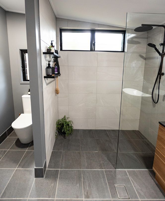 A bathroom with a walk in shower , toilet and window.