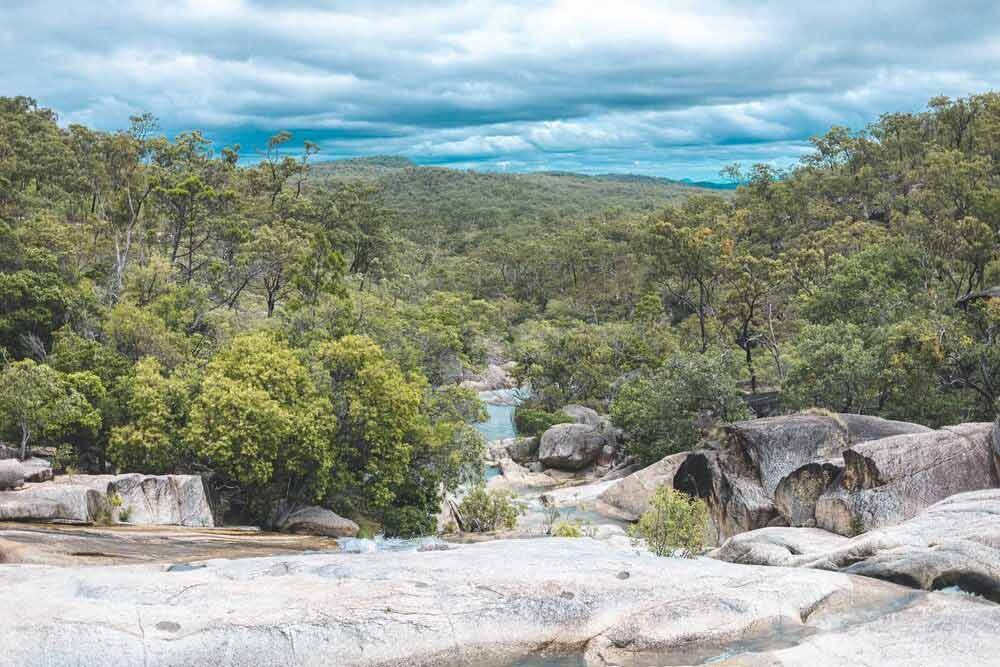 A River Runs Through A Lush Green Forest Surrounded By Rocks And Trees — Omni Builders In Mareeba, QLD