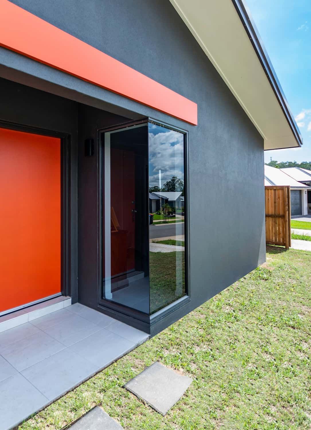 A Black House With An Orange Door And A Large Window — Omni Builders In Bungalow, QLD