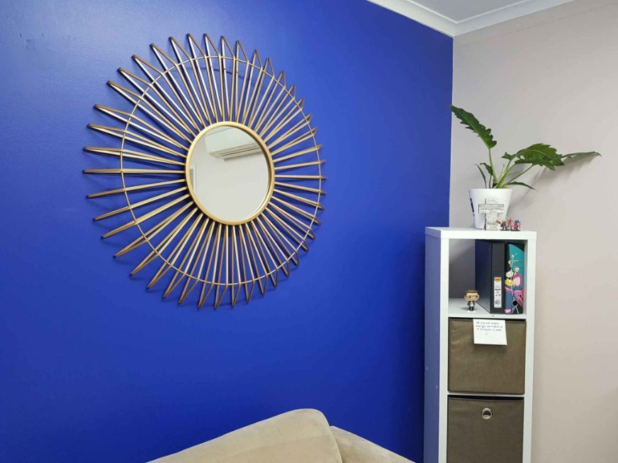 A Living Room With a Blue Wall , a Couch , a Mirror and a Shelf — Omni Builders In Bungalow, QLD