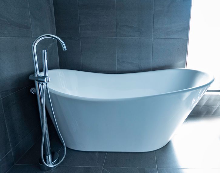 A White Bathtub is Sitting in a Bathroom Next to a Window — Omni Builders In Bungalow, QLD