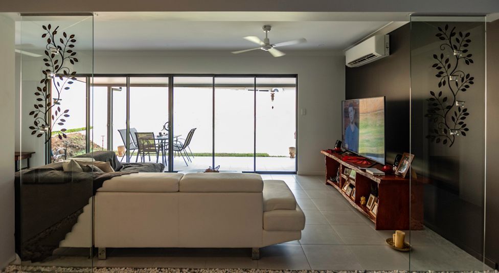 A Living Room With a Couch , Television , and Sliding Glass Doors — Omni Builders In Bungalow, QLD