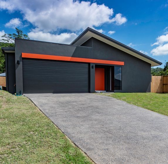 A Black and Orange House With a Driveway Leading to It — Omni Builders In Bungalow, QLD