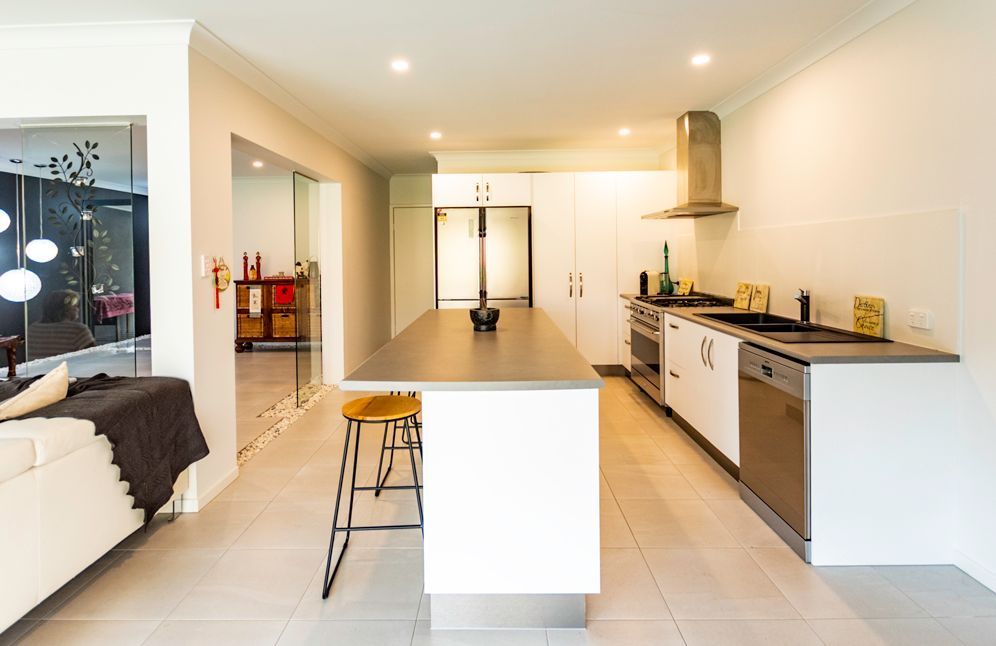 A Kitchen With White Cabinets and a Large Island in the Middle — Omni Builders In Bungalow, QLD