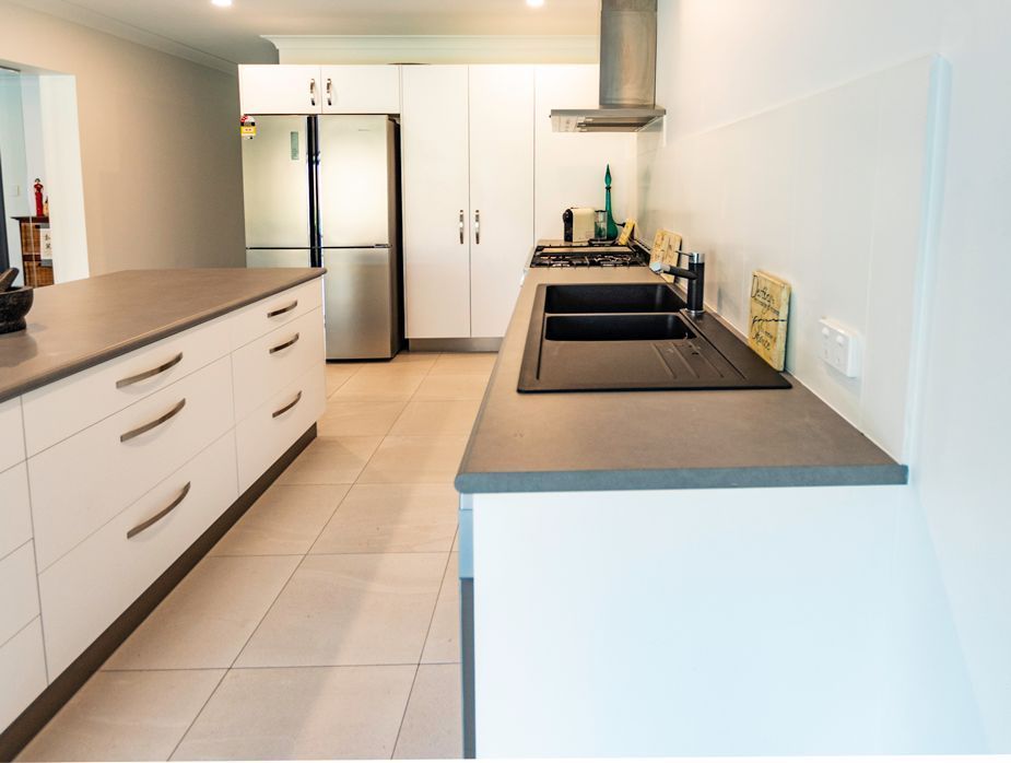 A Kitchen With White Cabinets and a Black Sink — Omni Builders In Bungalow, QLD