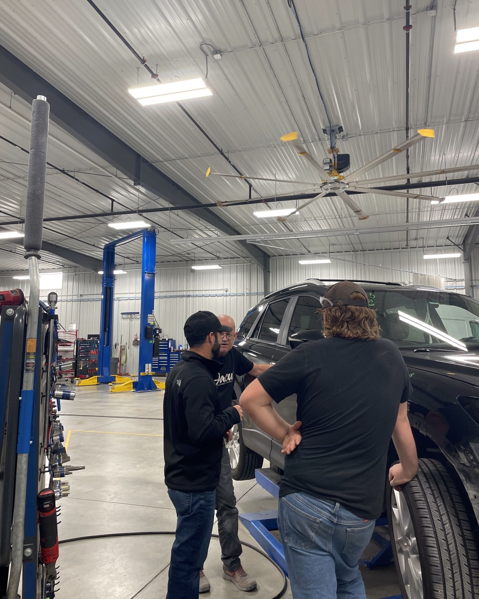 Two men are working on a car in a garage.