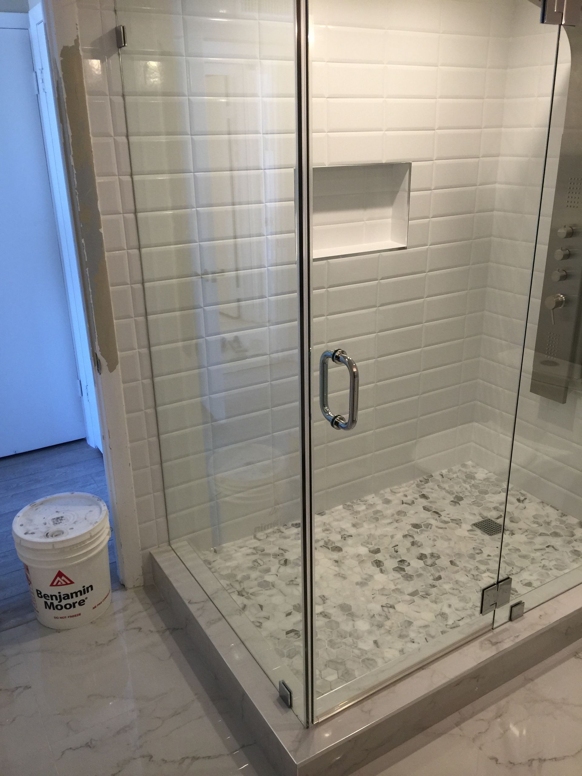 A bathroom with a walk in shower with a glass door.