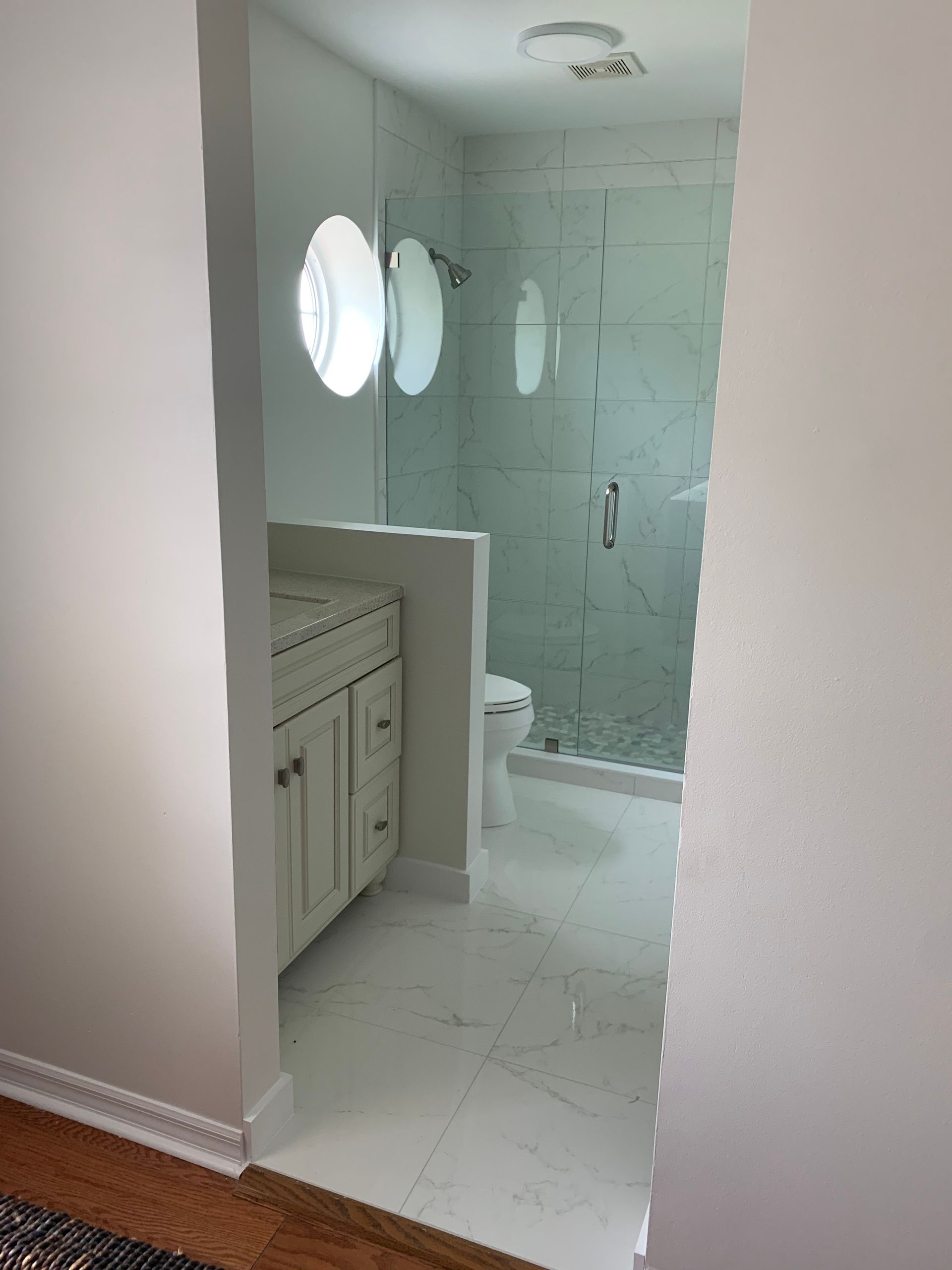 A bathroom with a walk in shower , sink , toilet and mirror.