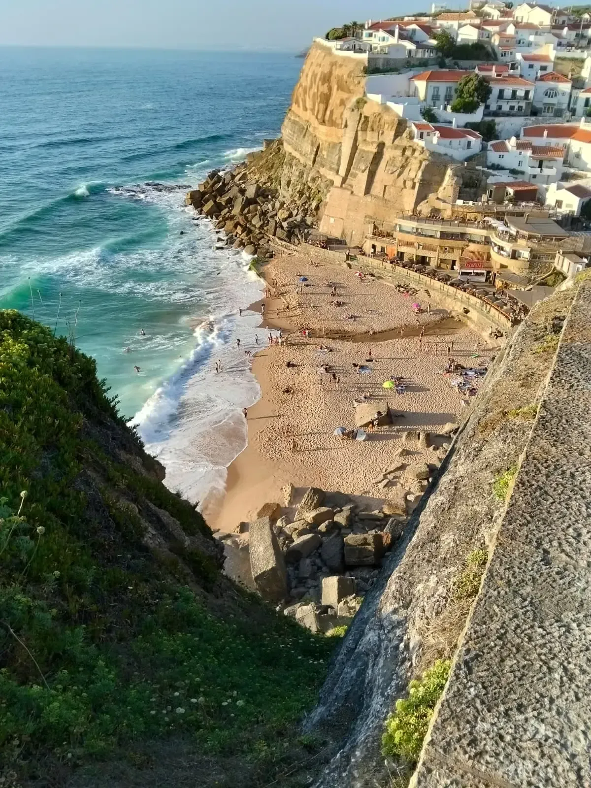 Sandy beach below golden cliffs and a seaside village in Azenhas do Mar, Portugal