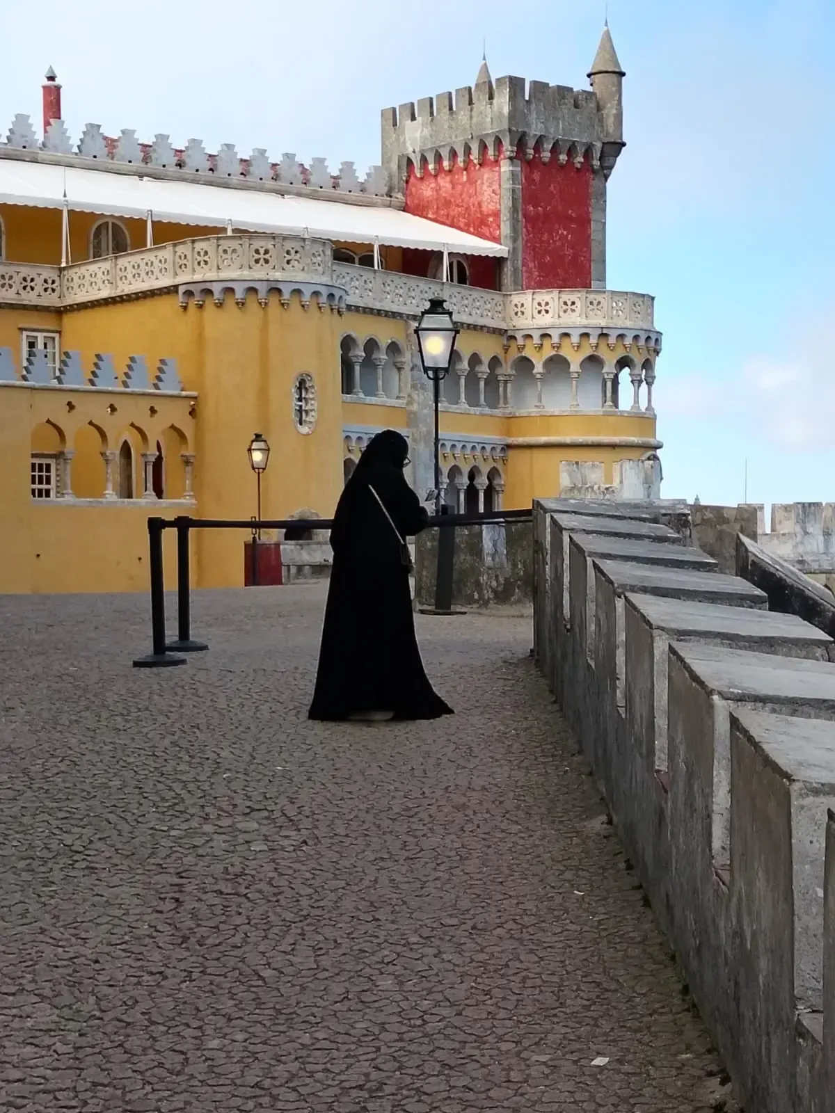 Visitor in a black cape on the colorful terraces of Pena Palace, Sintra