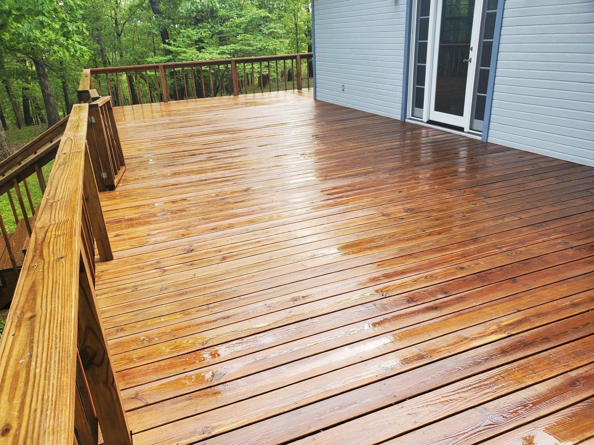 A wooden deck is sitting in front of a white brick house.