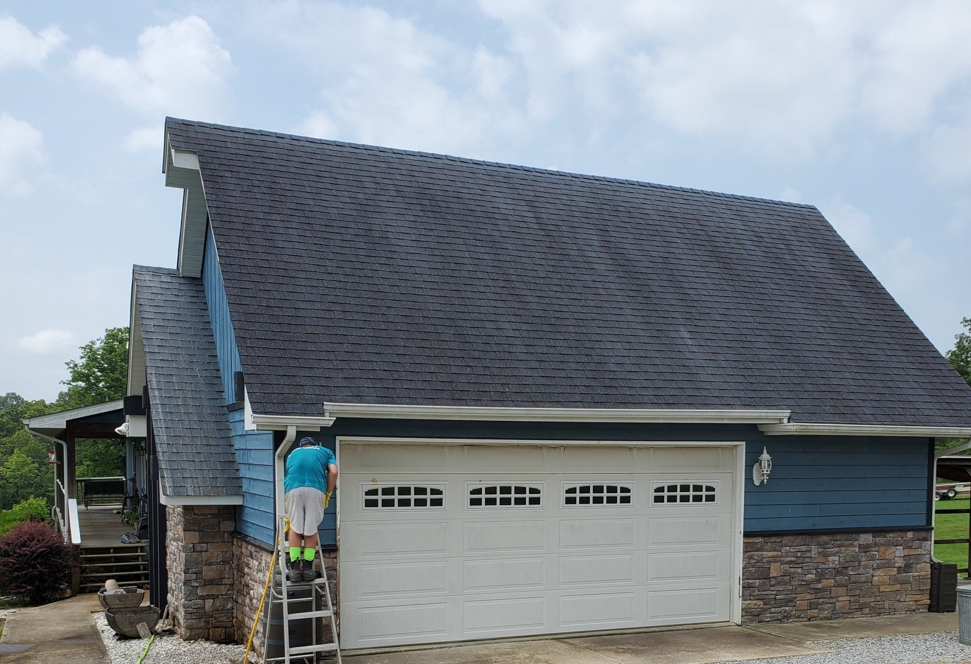 A man is painting the roof of a house.