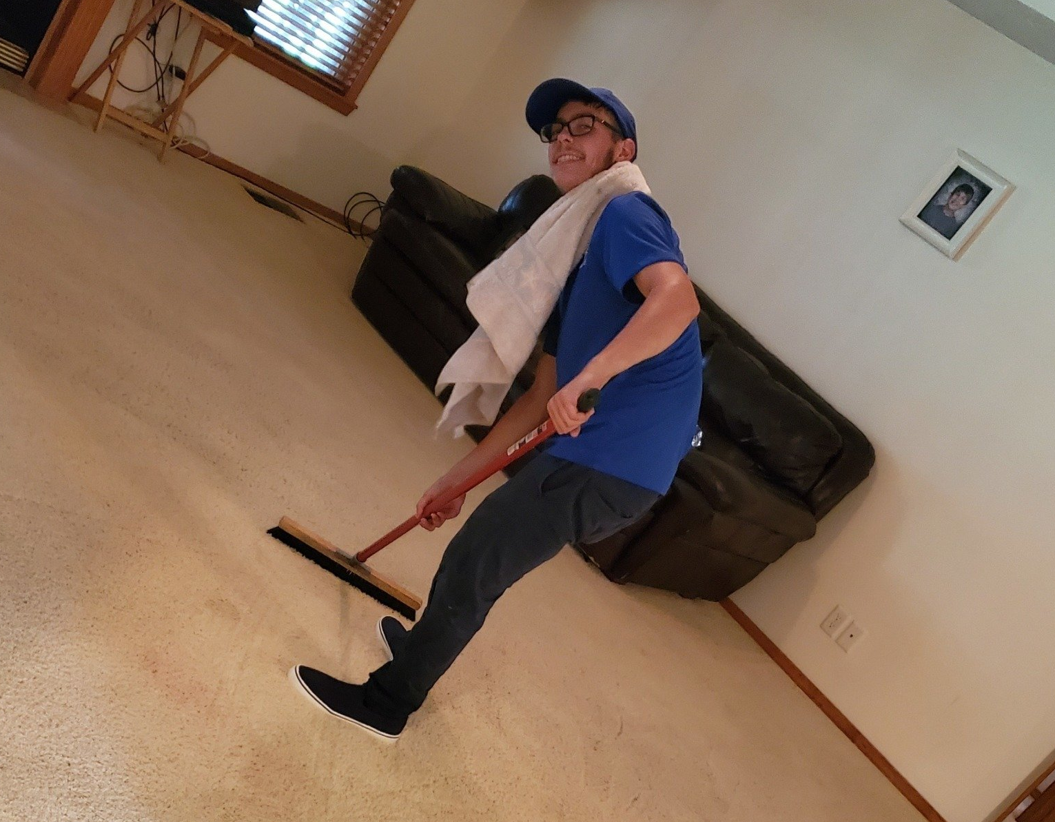 A man in a blue shirt is sweeping the floor