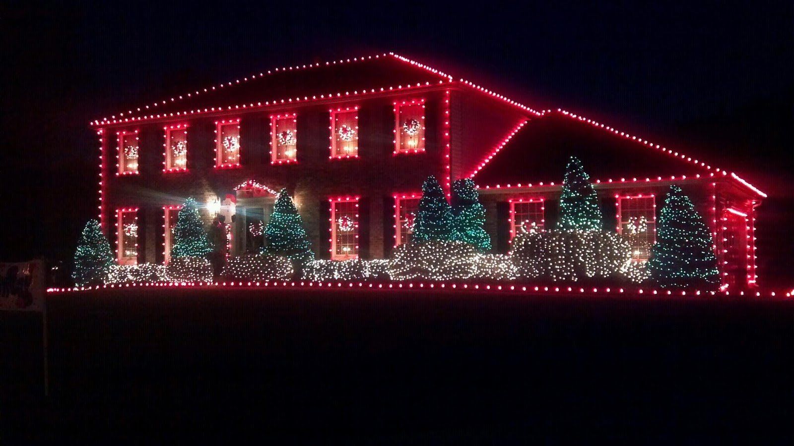A large house is lit up with red christmas lights