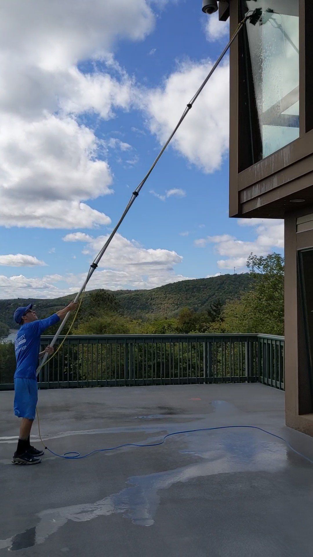 A man is cleaning a window with a long pole.
