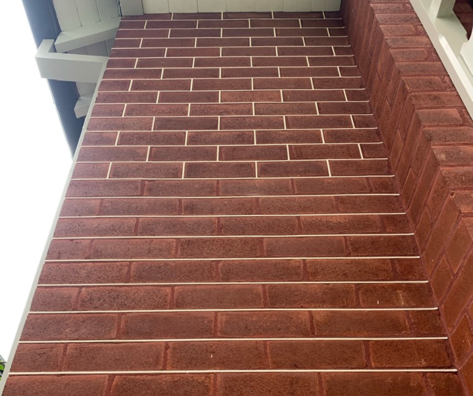 Brick staircase viewed from below with white railings and a ceiling above