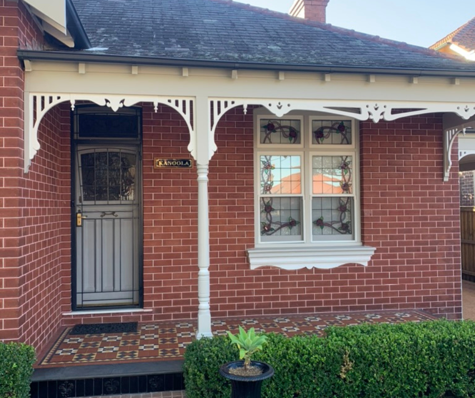 Brick house front porch with black door, white trim, bay window, and trimmed hedge. Brick house front porch with black door, white trim, bay window, and trimmed hedge.