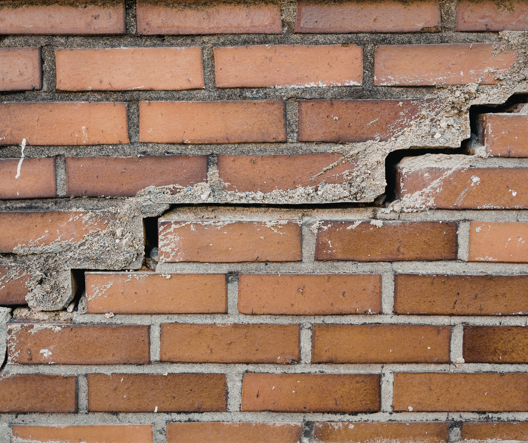 Cracked brick wall with a large horizontal fracture and missing mortar sections Cracked brick wall with a large horizontal fracture and missing mortar sections