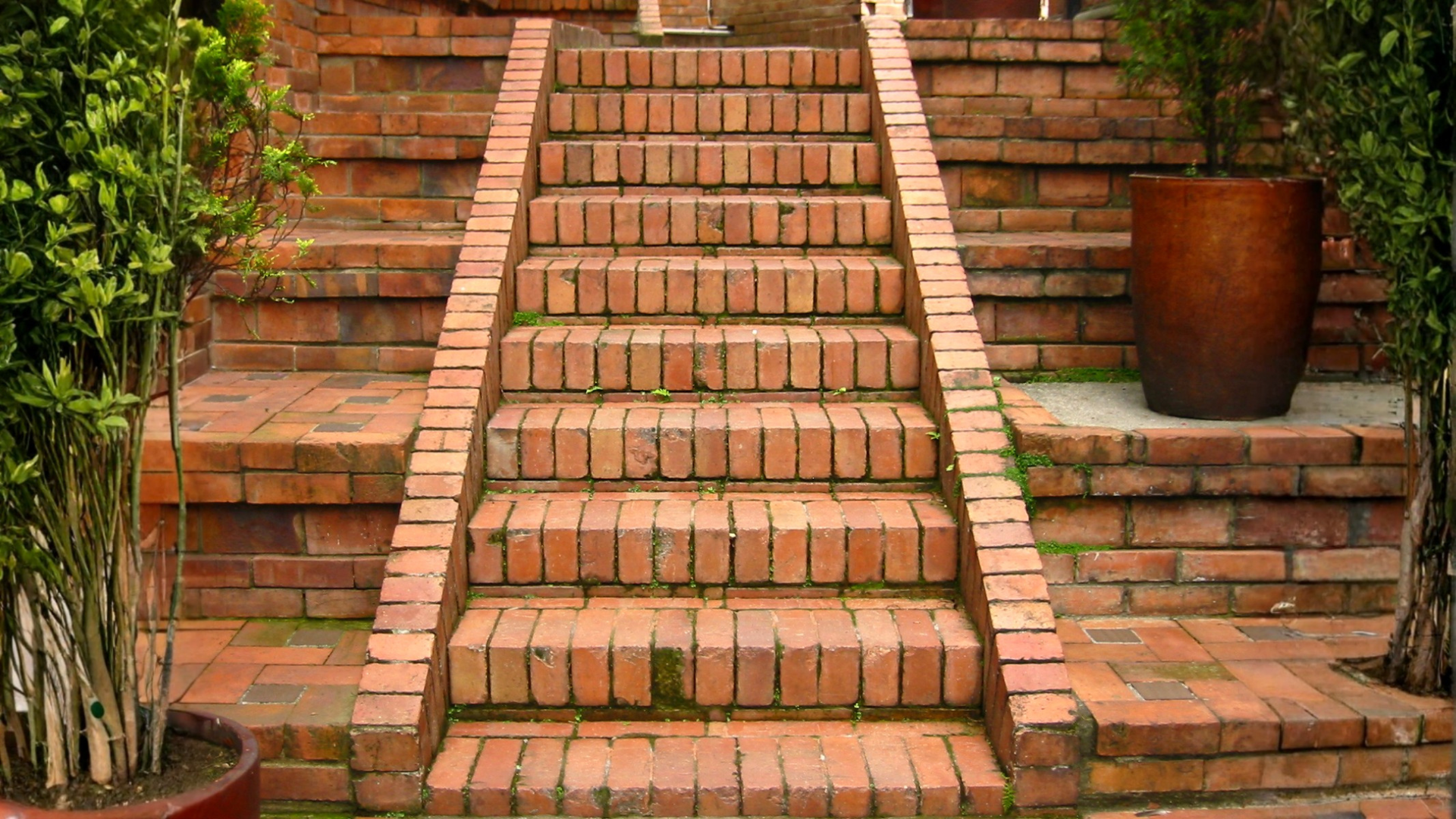 Brick staircase in a garden with terracotta pots and lush greenery on both sides Brick staircase in a garden with terracotta pots and lush greenery on both sides