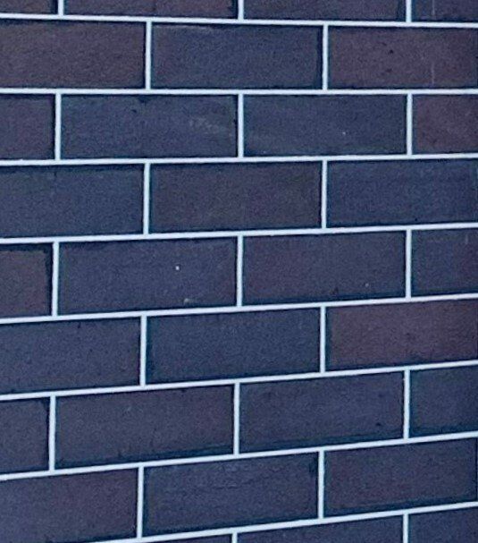 Close-up of a dark brick wall with light gray mortar lines.