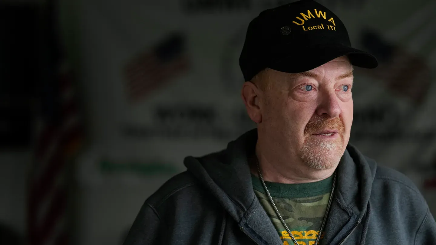 a man wearing a hat and a hoodie is looking at the camera.