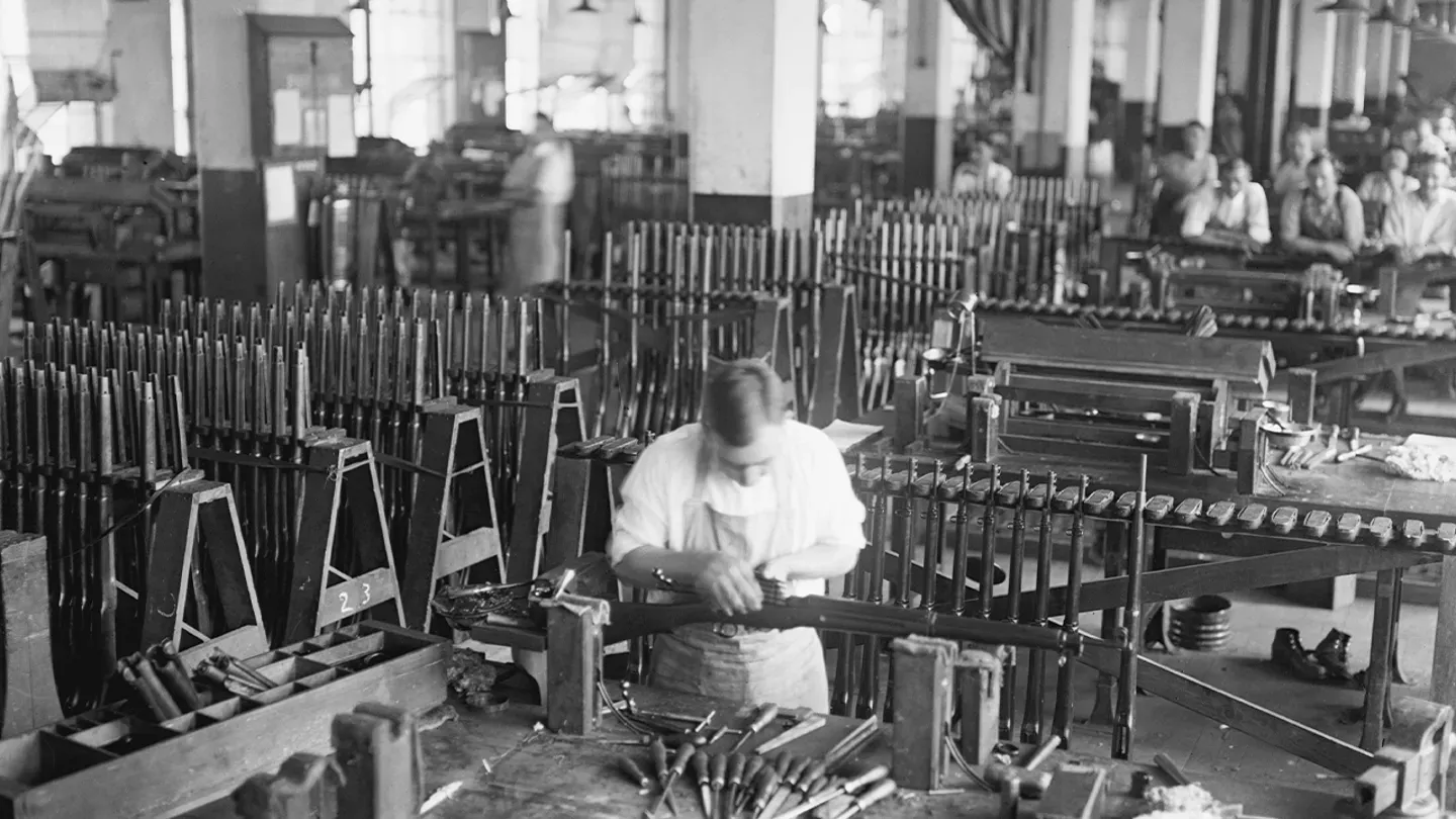 a black and white photo of a man working in a factory.