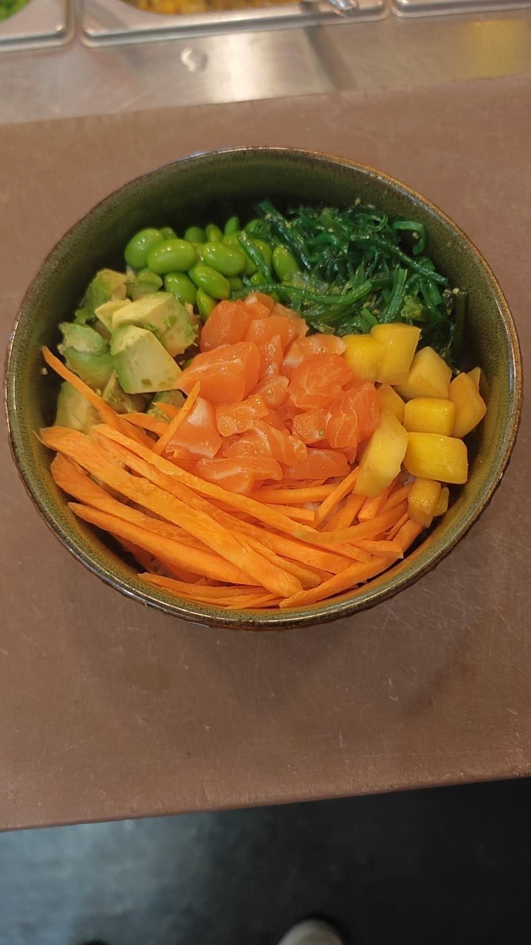 Una ciotola di verdure tritate: carote, peperoni arancioni e gialli, broccoli e fagiolini su un piano di lavoro.