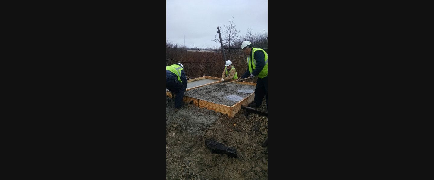 A group of construction workers are working on a concrete slab.