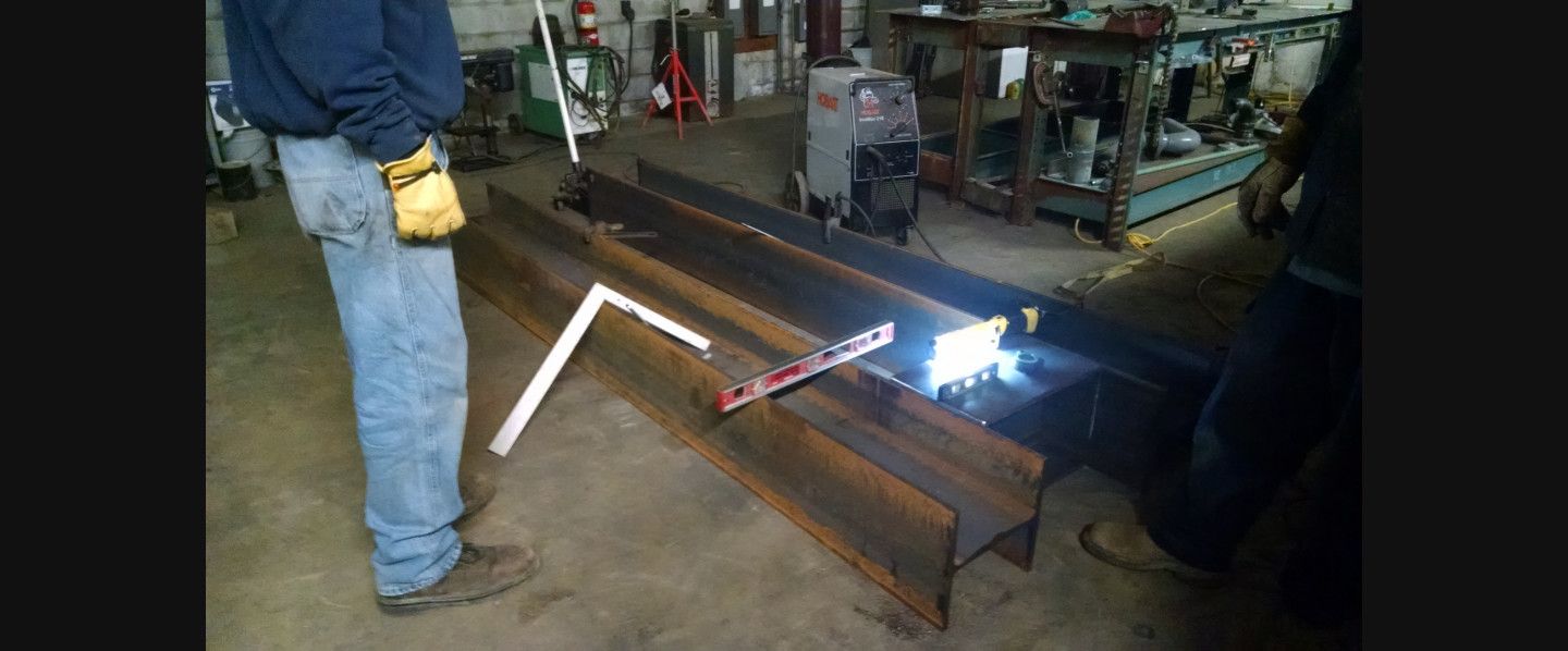 A man is welding a piece of metal in a factory.