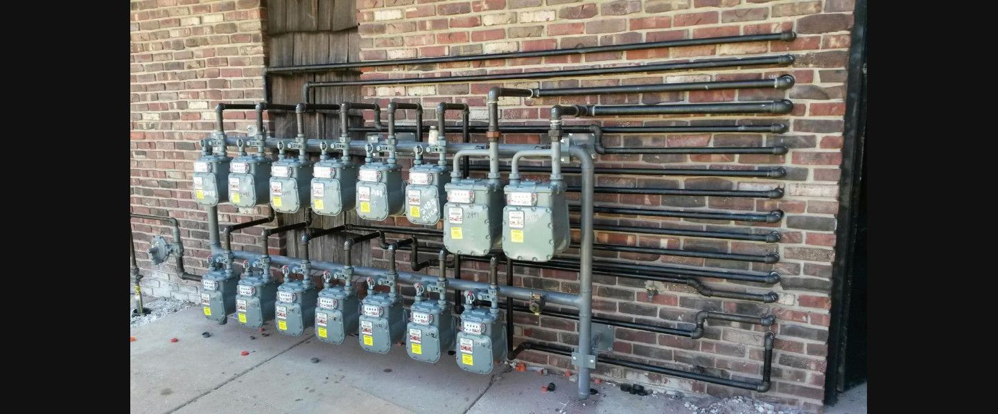 A row of gas meters sitting on the side of a brick building.