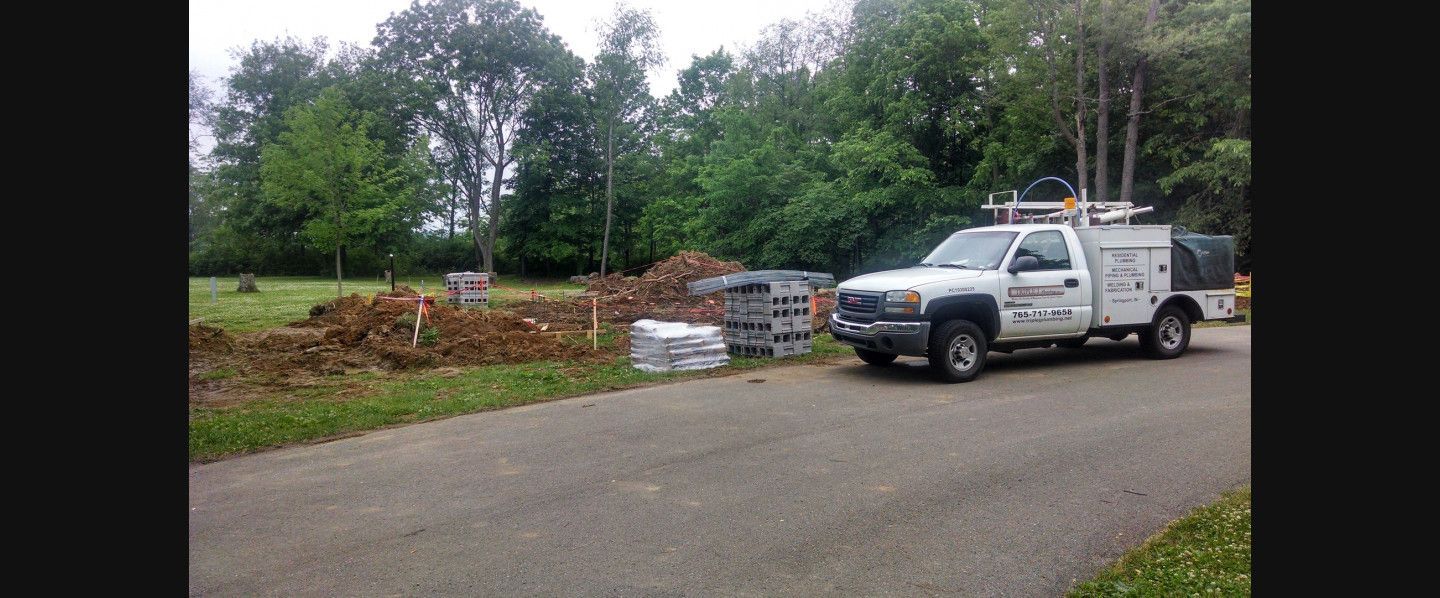A white truck is parked on the side of a road next to a pile of dirt.