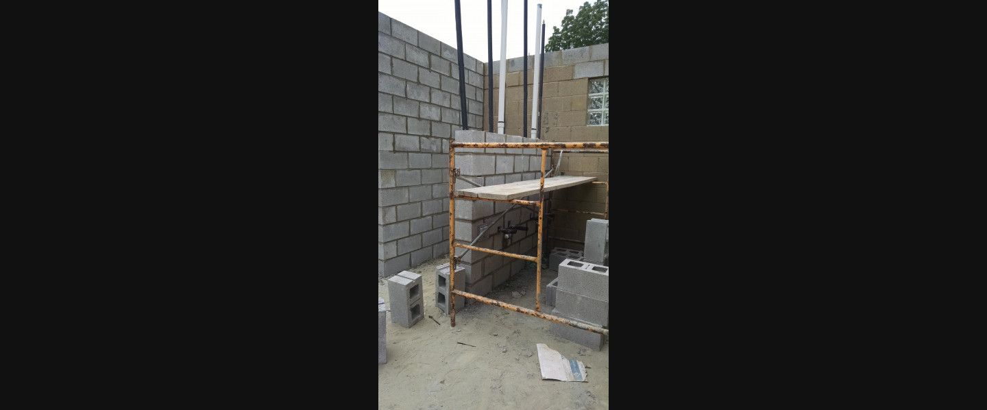 A scaffolding is sitting in front of a brick wall.