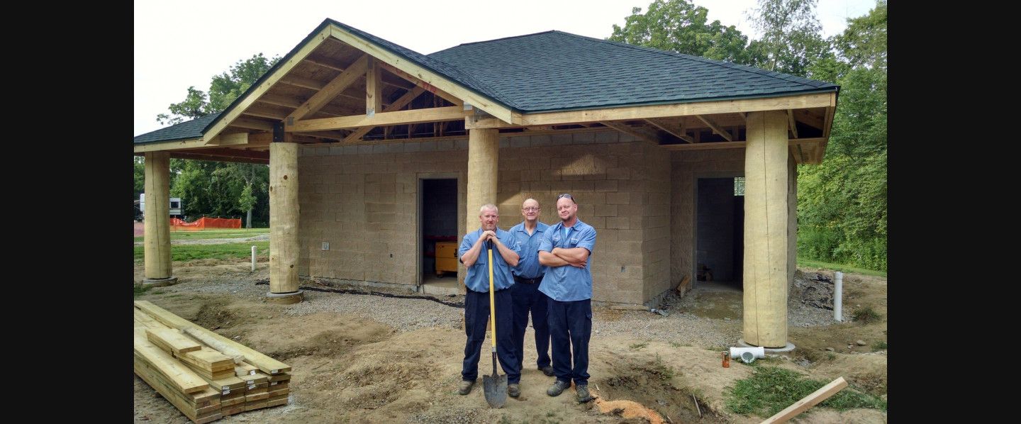 Three men are standing in front of a house under construction.