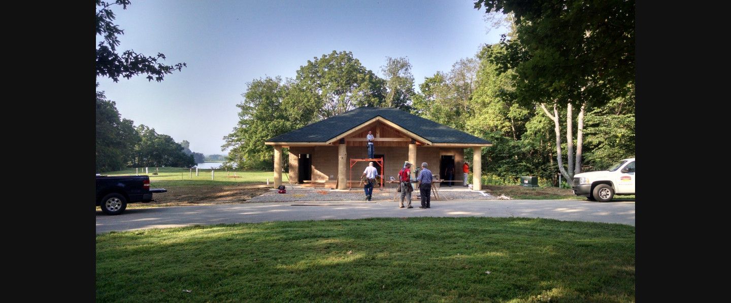 A group of people are standing in front of a house that is being built.