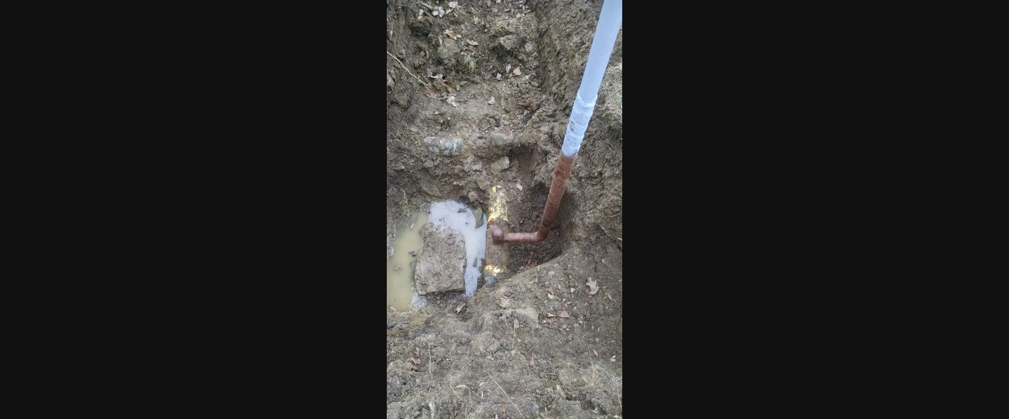 A person is cutting a hole in the ground with a saw.
