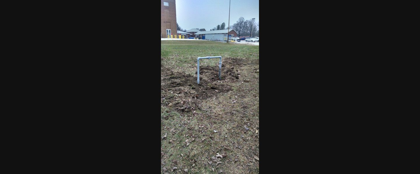 A person is digging a hole in the ground in a field.