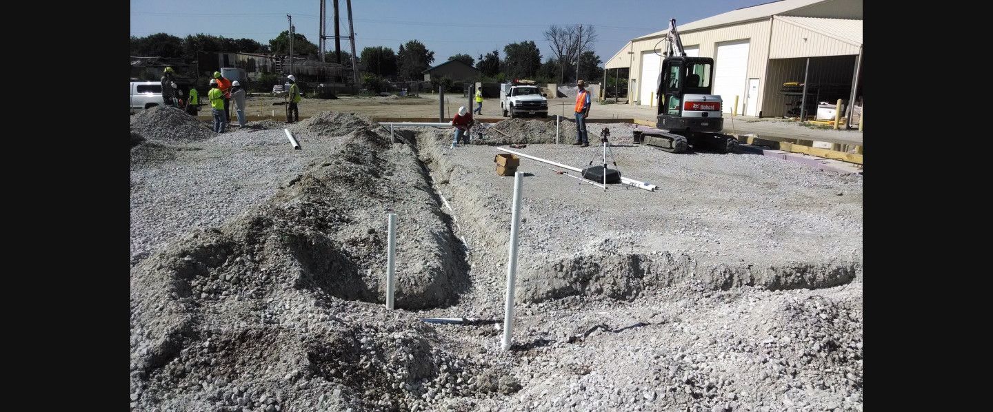 A group of construction workers are working on a gravel road.