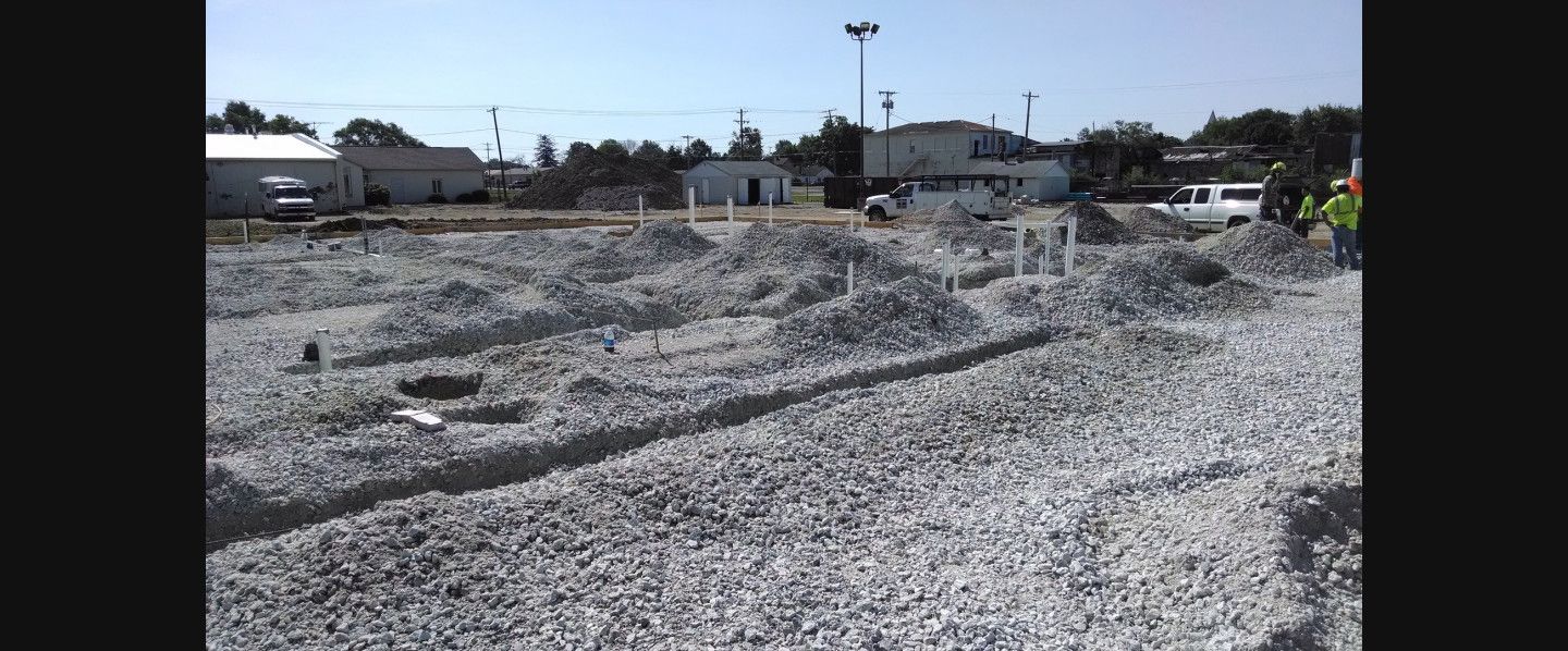 A large pile of gravel is sitting on top of a dirt field.