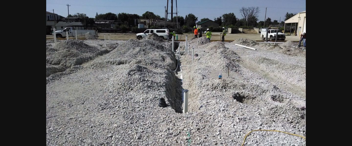 A group of construction workers are working on a gravel road.
