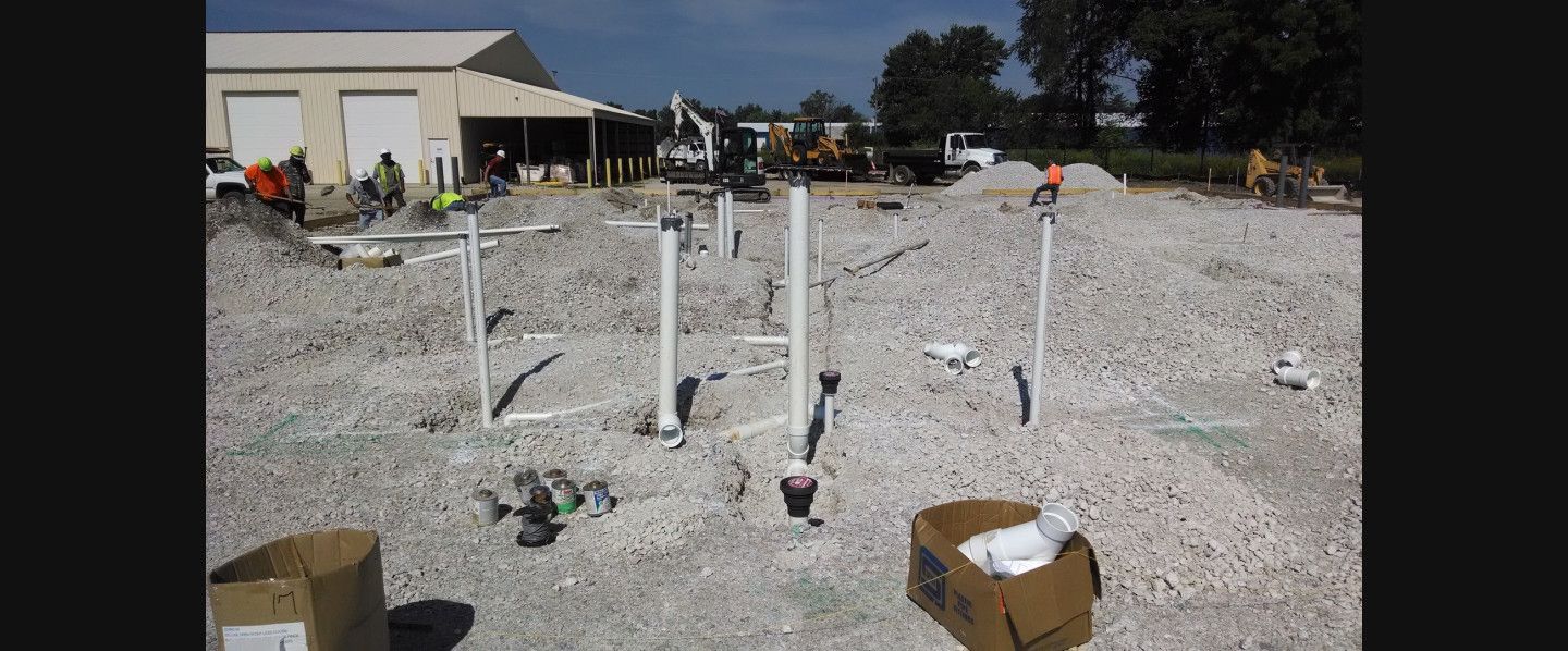 A construction site with a lot of pipes and boxes on the ground.